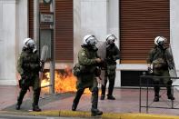 <p>Riot police walk next to flames from a petrol bomb during a 24-hour general strike against the latest round of austerity in Athens, Greece, May 17, 2017. (Alkis Konstantinidis/Reuters) </p>