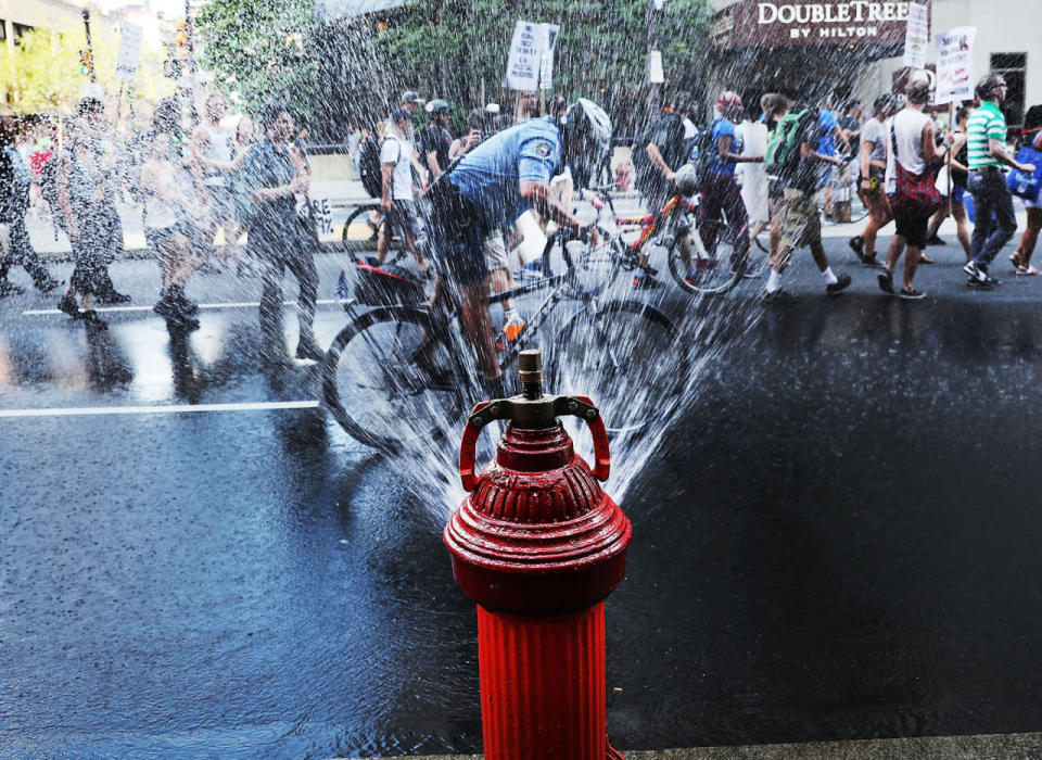 <p>A police officer cools off by riding through an open fire hydrant on a hot afternoon during a Black Lives Matter protest in downtown Philadelphia during the Democratic National Convention on July 26, 2016 in Philadelphia, Pa. (Photo: Spencer Platt/Getty Images)</p>