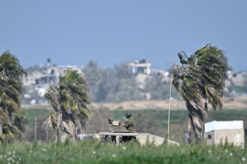 Soldier stands in vehicle as it passes near Israel-Gaza border