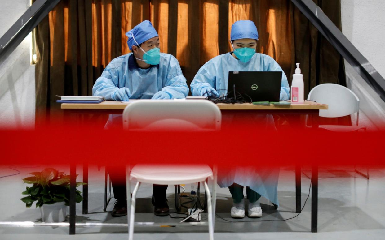 Medical workers wait to register people before they receive a dose of a coronavirus vaccine, in Beijing - Reuters