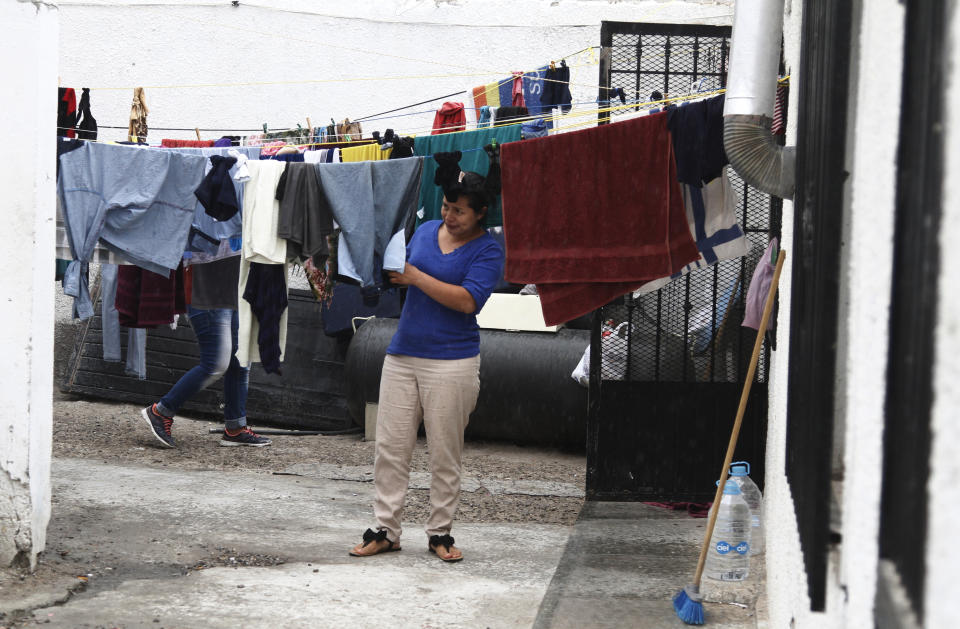 In this June 10, 2019, Mirna Esperanza Martinez, from El Salvador removes clothes from a line as it starts to rain at the Buen Pastor migrant shelter in Ciudad Juarez, Mexico. She was returned to Mexico after applying for asylum in the U.S. with her husband and two older children. Her youngest son is a U.S. citizen staying with family members in Boston. (AP Photo/Cedar Attanasio)