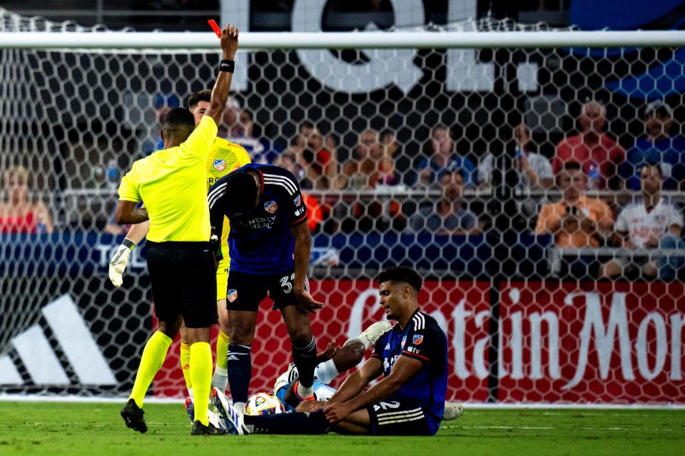 FC Cincinnati defender Miles Robinson (seated) receives a red card in the second half of Saturday night's surprising 3-1 loss to Charlotte FC at TQL Stadium.