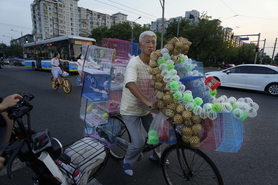 A street vendor selling birds and crickets cycles on the road in Beijing, Tuesday, Aug. 15, 2023. Chinese leader Xi Jinping has called for patience in a speech released as the ruling Communist Party tries to reverse a deepening economic slump and said Western countries are "increasingly in trouble" because of their materialism and "spiritual poverty." (AP Photo/Ng Han Guan)