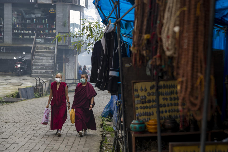 Exile Tibetan Buddhist monks wearing masks as a precautionary measure against the coronavirus walks in a deserted market area in Dharmsala, India, Friday, Sept. 11, 2020. India's coronavirus cases are now the second-highest in the world and only behind the United States. (AP Photo/Ashwini Bhatia)