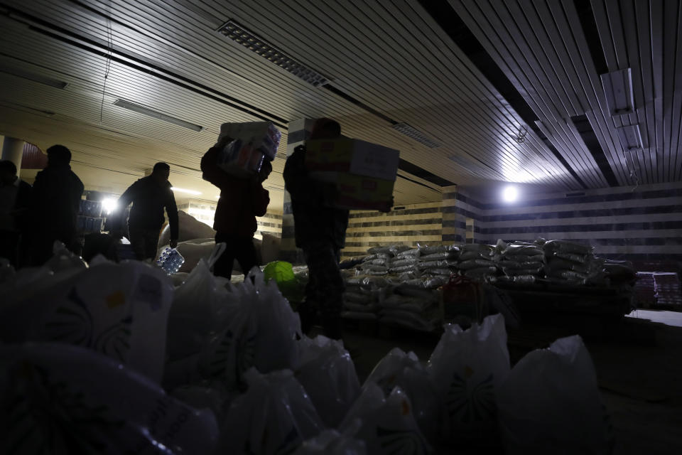 Volunteers carry food boxes to distribute to displaced people following a devastating earthquake, in the coastal city of Latakia, Syria, Friday, Feb. 10, 2023. The 7.8 magnitude earthquake that hit Turkey and Syria, killing more than 23,000 this week has displaced millions of people in war-torn Syria. The country's 12-year-old uprising turned civil war had already displaced half the country's pre-war population of 23 million before the earthquake. (AP Photo/Omar Sanadiki)