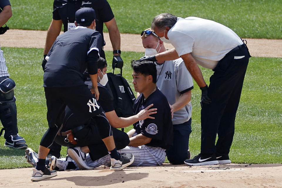 New York Yankees pitcher Masahiro Tanaka is tended to by team medical personnel after being hit by a ball off the bat of Yankees Giancarlo Stanton during a baseball a workout at Yankee Stadium in New York, Saturday, July 4, 2020. (AP Photo/Adam Hunger)