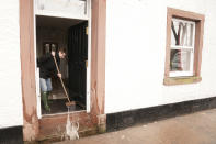 A resident sweeps floodwater from a property in Appleby-in-Westmorland, Cumbria. (PA)