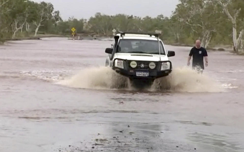 In this image made off video, a car drives through flooded road in Port Hedland, Western Australia, Monday, March 25, 2019. Slow-moving Cyclone Veronica that lashed northwest Australia was weakening on Monday. (The Australian Broadcasting Corp via AP)