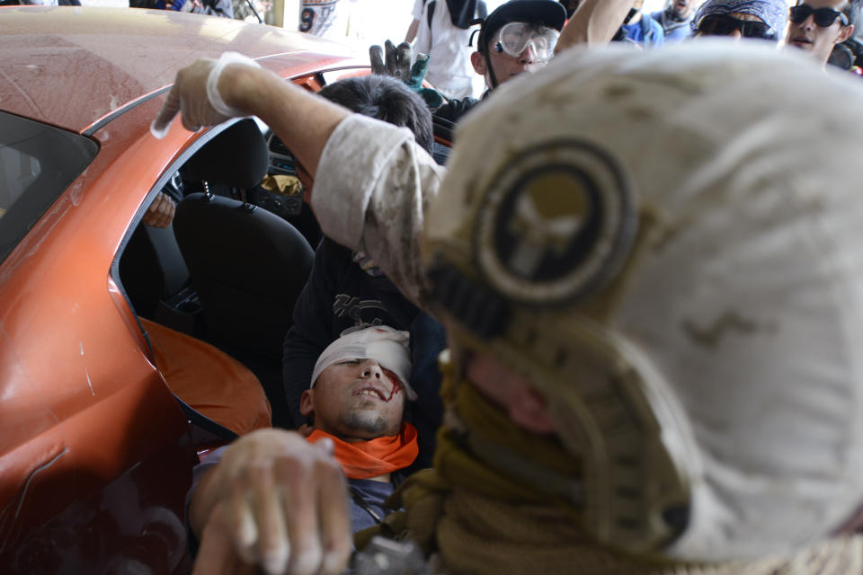 FILE - In this Oct. 25, 2019 file photo, an anti-government protester injured during clashes with police is placed into the backseat of a car in Valparaiso, Chile. In less than a month, more than 230 Chileans have lost sight in one eye, mostly due to the impact of pellets fired by the police during clashes with protesters demanding greater equality and improved social services. (AP Photo/Matias Delacroix, File)