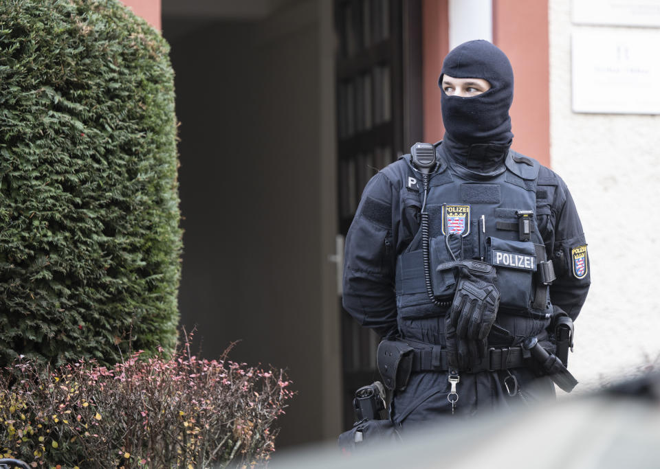 FILE - Police officers stand by a searched property in Frankfurt during a raid against so-called 'Reich citizens' in Frankfurt, Germany, Wednesday, Dec. 7, 2022. Nine people charged in connection with an alleged far-right plot to topple the German government are going on trial in one of three cases linked to the plot that came to light in late 2022. The trial that opens Monday in Stuttgart is the first one and focused on those defendants of the so-called Reich Citizens group who allegedly were part of the so-called military arm. (Boris Roessler/dpa via AP, File)