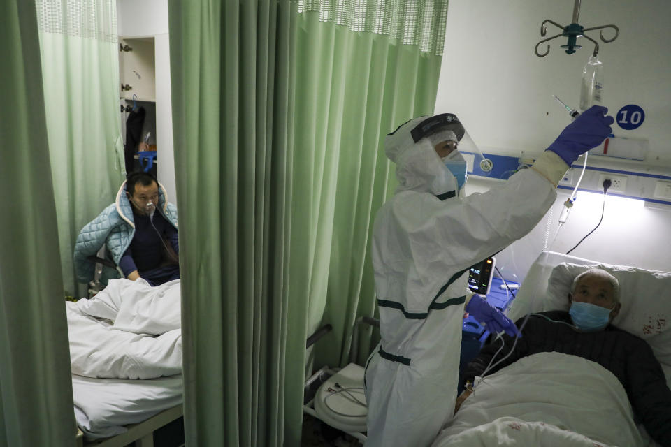 In this Thursday, Feb. 6, 2020, photo, a nurse checks on a patient in the isolation ward for 2019-nCoV patients at a hospital in Wuhan in central China's Hubei province. The number of confirmed cases of the new virus has risen again in China on Saturday, Feb. 8, 2020, as the ruling Communist Party faced anger and recriminations from the public over the death of a doctor who was threatened by police after trying to sound the alarm about the disease over a month ago. (Chinatopix via AP)