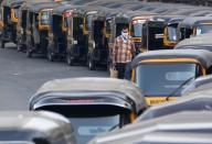 A man wearing a handkerchief as a mask moves past parked autorickshaw during a curfew to limit the spreading of coronavirus disease (COVID-19), in Mumbai