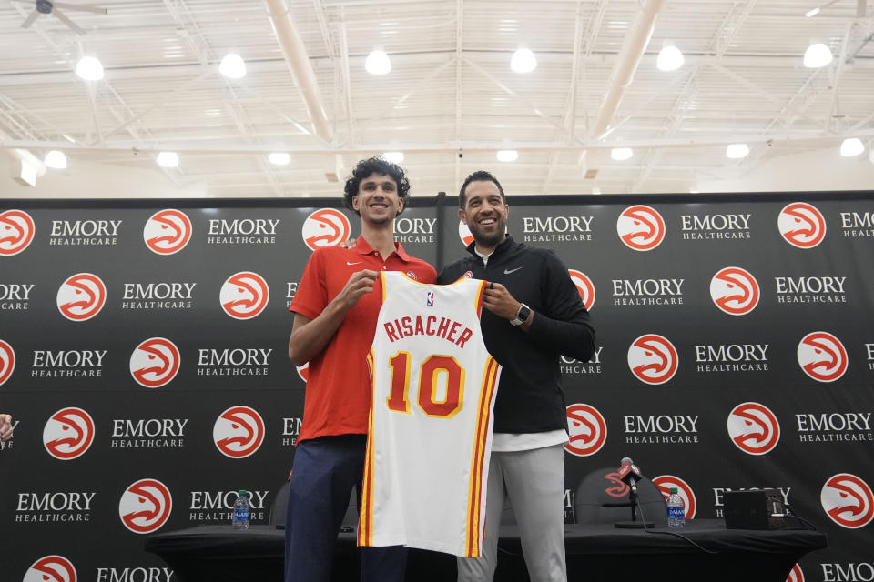 Atlanta Hawks' Zaccharie Risacher, left, and General Manager Landry Fields, right, hold up Risacher's jersey after an NBA basketball news conference, Friday, June 28, 2024, in Atlanta. Risacher was selected as the first overall pick by the Atlanta Hawks in the first round of the NBA basketball draft. (AP Photo/Brynn Anderson)