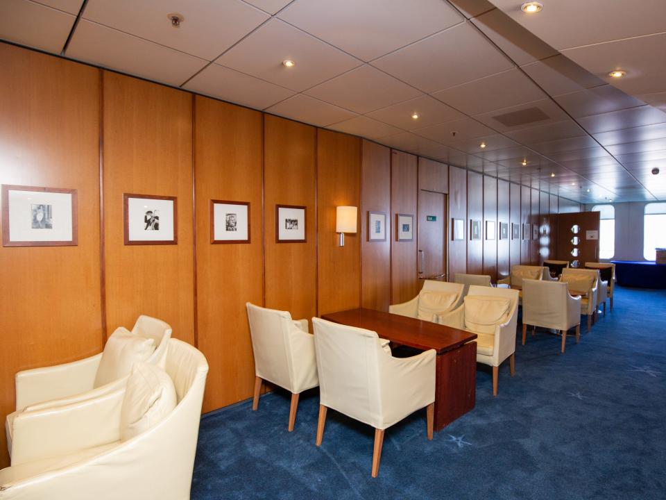 A collection of lounge chairs and tables next to a wooden wall with pictures.