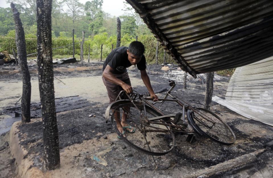 A villager lifts a burnt bicycle after homes were set on fire in ethnic violence at Khagrabari village, in the northeastern Indian state of Assam, Saturday, May 3 2014. Police in India arrested 22 people after separatist rebels went on a rampage, burning homes and killing dozens of Muslims in the worst outbreak of ethnic violence in the remote northeastern region in two years, officials said Saturday. (AP Photo/Anupam Nath)