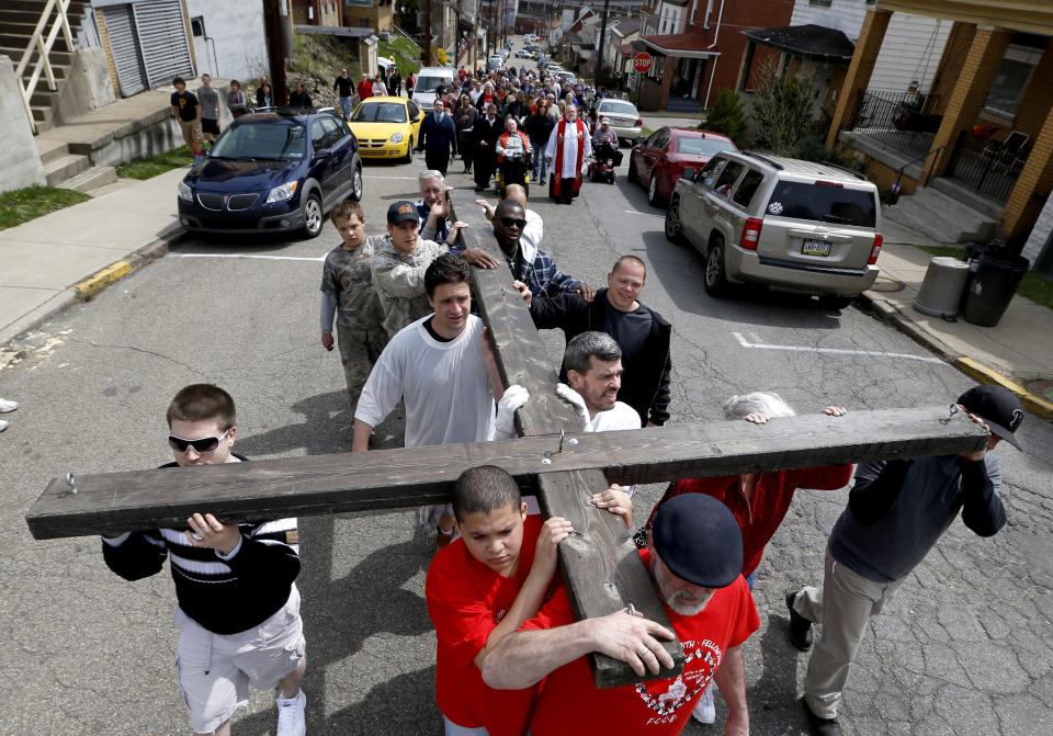 Volunteers carry a wooden cross walk in a procession through the streets of Etna, Pa., a Pittsburgh suburb, on Good Friday, Friday, April 18, 2014, as part of their annual "Drama of The Cross". Clergymen from Christian churches in the borough organize a trek with volunteers carrying the wooden cross through borough streets to the cemetery as part of their services for the holiday. (AP Photo/Keith Srakocic)