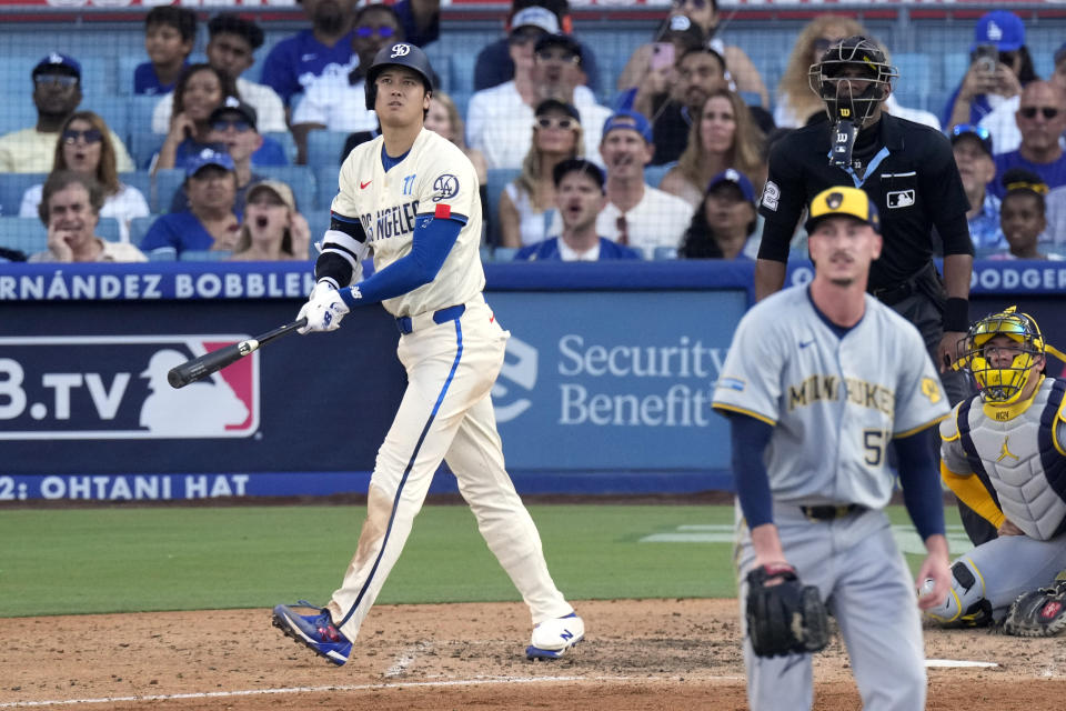 Los Angeles Dodgers' Shohei Ohtani, left, heads to first for a solo home run as Milwaukee Brewers relief pitcher Bryan Hudson, second from left, and catcher William Contreras, right, watch along with home plate umpire Edwin Moscoso during the eighth inning of a baseball game Saturday, July 6, 2024, in Los Angeles. (AP Photo/Mark J. Terrill)