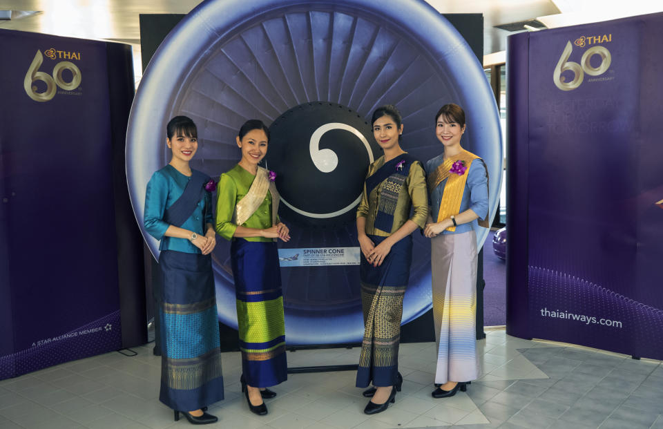 Flight attendants pose for a photo in a flight-themed restaurant at the Thai Airways head office in Bangkok, Thailand on Oct. 3, 2020. The airline is selling time on its flight simulators to wannabe pilots while its catering division is serving meals in a flight-themed restaurant complete with airline seats and attentive cabin crew. The airline is trying to boost staff morale, polish its image and bring in a few pennies, even as it juggles preparing to resume international flights while devising a business reorganization plan. (AP Photo/Sakchai Lalit)