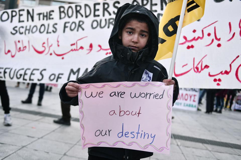 A boy carries a sign as migrants and refugees demonstrate in Athens on January 21, 2017.