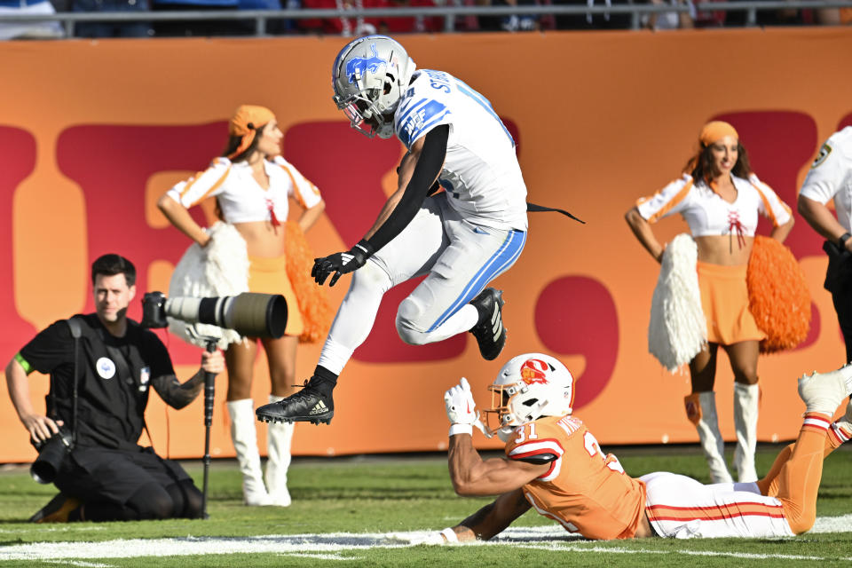 Detroit Lions wide receiver Amon-Ra St. Brown (14) avoids the tackle of Tampa Bay Buccaneers safety Antoine Winfield Jr. (31) on a 27-yard touchdown reception during the first half of an NFL football game Sunday, Oct. 15, 2023, in Tampa, Fla. (AP Photo/Jason Behnken)