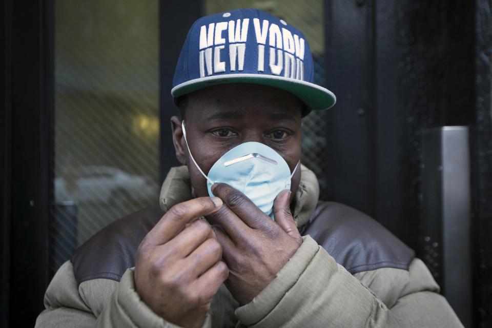 A pedestrian adjusts his mask as smoke surrounds the perimeter of the scene after an explosion that leveled two apartment buildings in the East Harlem neighborhood of New York, Wednesday, March 12, 2014. Con Edison spokesman Bob McGee says a resident from a building adjacent to the two that collapsed reported that he smelled gas inside his apartment, but thought the odor could be coming from outside. (AP Photo/John Minchillo)