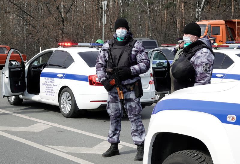 Law enforcement officers wearing protective masks stand guard at a checkpoint in Moscow