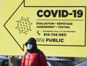 A man bundles up against the cold and wears a face mask for safety from COVID-19 as he walks past a testing clinic, Friday, Feb. 12, 2021, in Montreal. (Ryan Remiorz/The Canadian Press via AP)