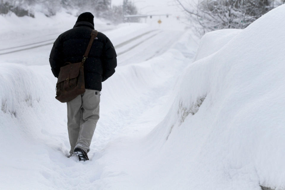 A man attempts to walk on an unplowed city sidewalk, Monday, Jan. 29, 2024, in Anchorage, Alaska. (AP Photo/Mark Thiessen)