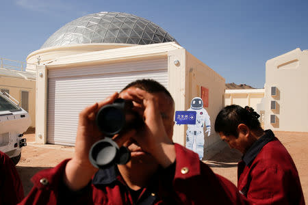 A staff member looks through a monocular at the C-Space Project Mars simulation base in the Gobi Desert outside Jinchang, Gansu Province, China, April 17, 2019. REUTERS/Thomas Peter