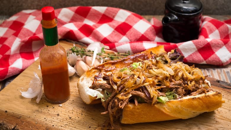 Beef and caramelized po'boy sandwich with hot sauce