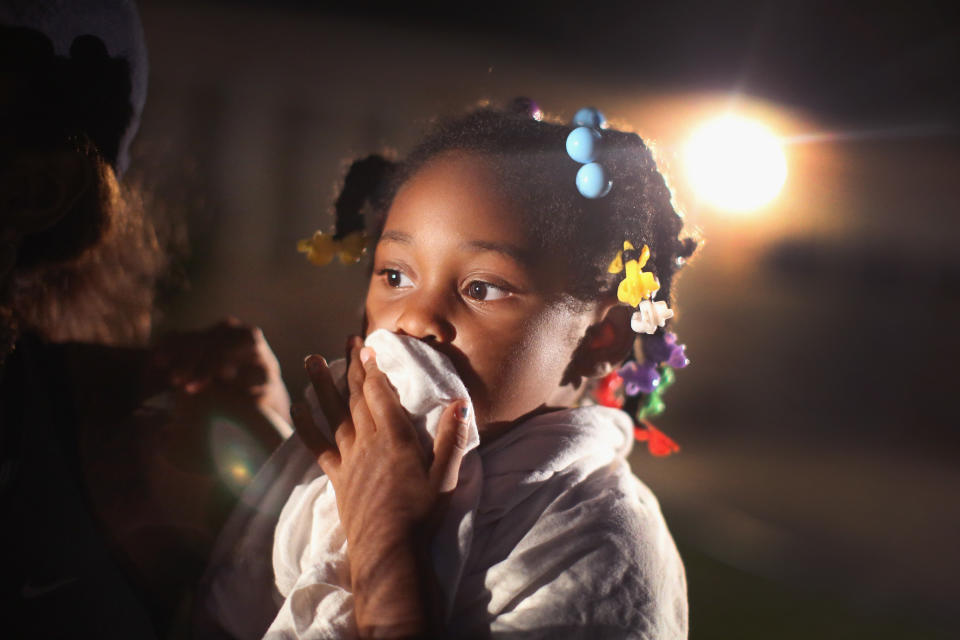 FERGUSON, MO - AUGUST 11:  A child uses a rag to shield her face from tear gas being fired by police who used it to force protestors from the business district into nearby neighborhoods on August 11, 2014 in Ferguson, Missouri. Police responded with tear gas and rubber bullets as residents and their supporters protested the shooting by police of an unarmed black teenager named Michael Brown who was killed Saturday in this suburban St. Louis community. Yesterday 32 arrests were made after protests turned into rioting and looting in Ferguson.  (Photo by Scott Olson/Getty Images)