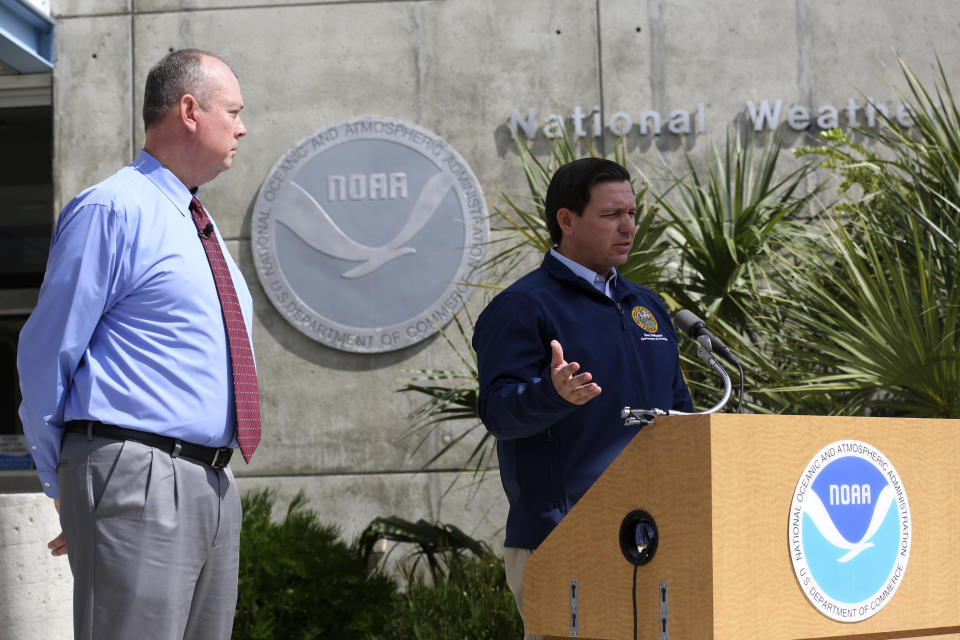 National Hurricane Center Director Ken Graham, left, looks on as Florida Gov. Ron DeSantis speaks about Tropical Storm Dorian outside of the the National Hurricane Center, Thursday, Aug. 29, 2019, in Miami. (AP Photo/Lynne Sladky)