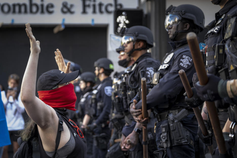 A woman kneels in front of officers Monday, June 1, 2020, in Seattle as peaceful protests took place across the city. (Dean Rutz/The Seattle Times via AP)