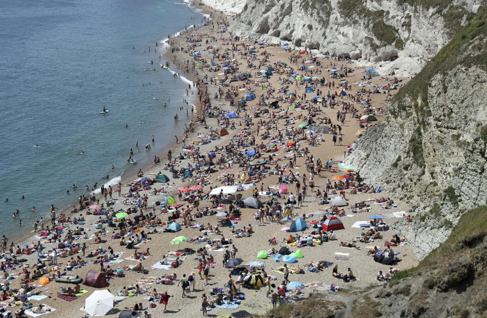 People on the beach at Durdle Door, as the public are being reminded to practice social distancing following the relaxation of coronavirus lockdown restrictions, near Lulworth in Dorset, England, Saturday, May 30, 2020. (Andrew Matthews/PA via AP)