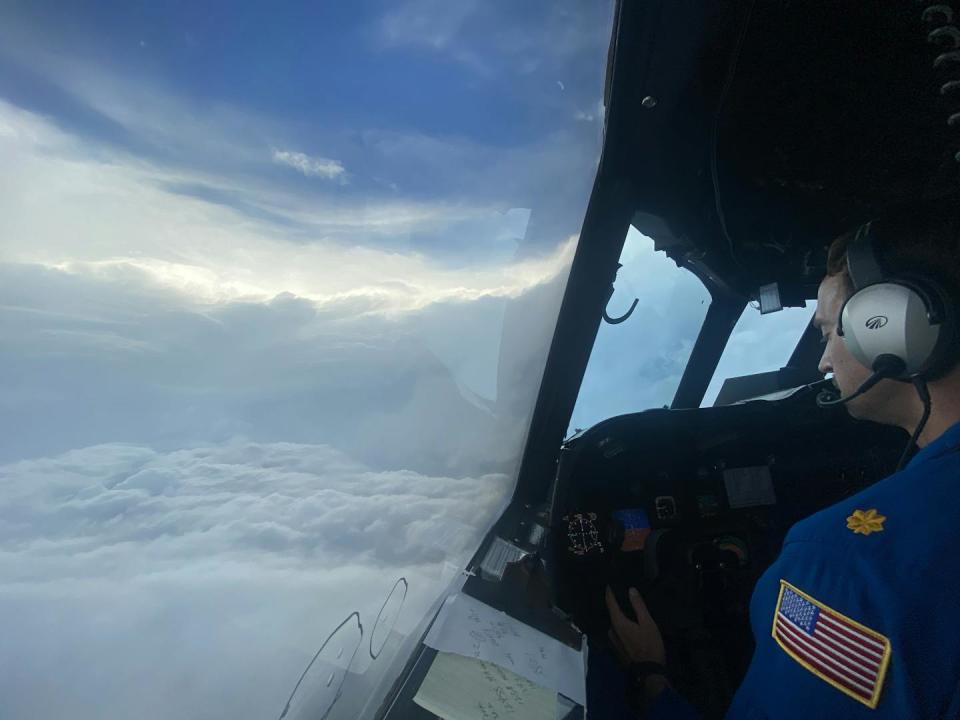 A pilot at the controls with the storm seen through the window