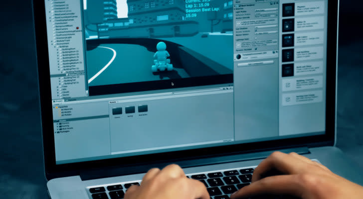 A developer works on a 3D racing game in the Unity engine on a laptop.