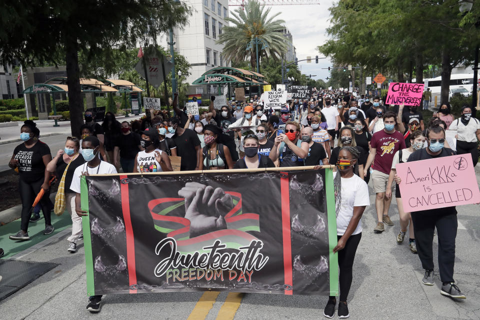 Demonstrators march through downtown Orlando, Fla., during a Juneteenth event Friday, June 19, 2020. Juneteenth marks the day in 1865 when federal troops arrived in Galveston, Texas, to take control of the state and ensure all enslaved people be freed, more than two years after the Emancipation Proclamation. (AP Photo/John Raoux)