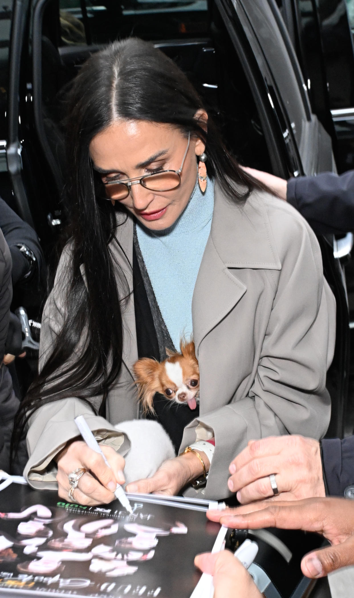 Pilaf, peeking out from Moore’s jacket, watches as the actress signs autographs.
