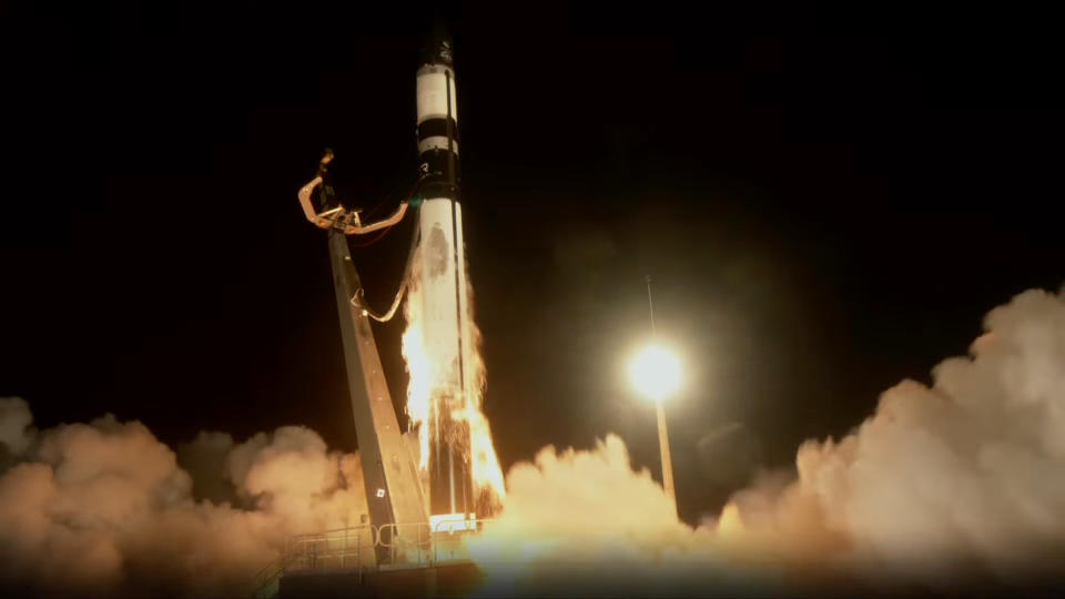  A black and white rocket launches from a pad at night. 