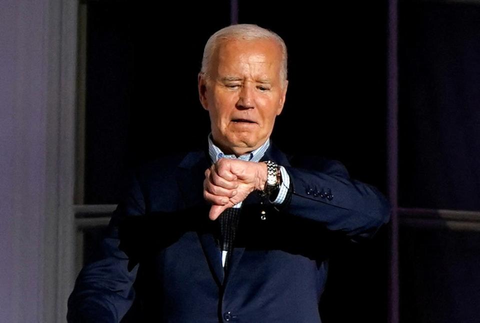 U.S. President Joe Biden looks at his watch as he stands on the balcony during an Independence Day celebration on the South Lawn of the White House