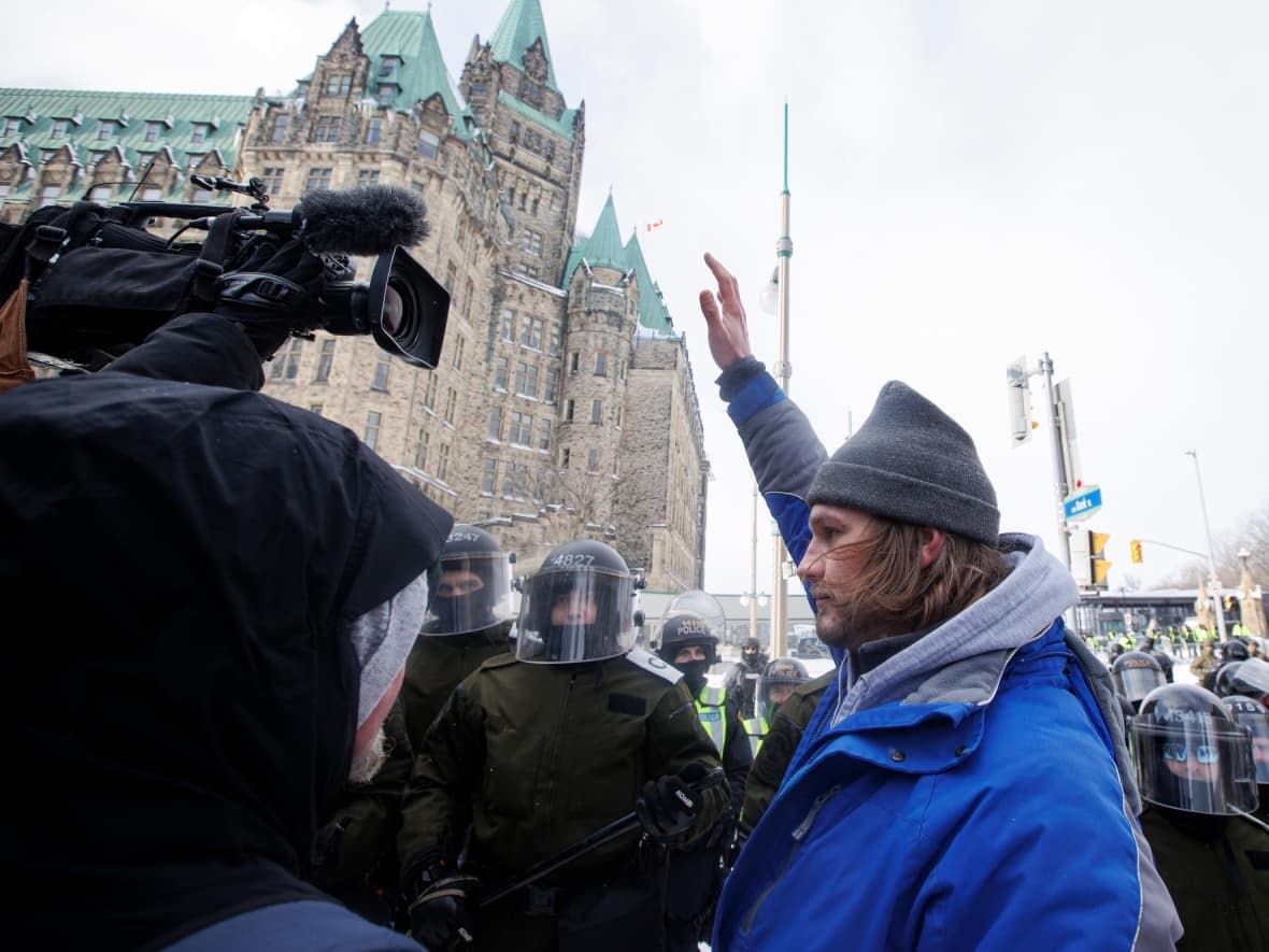 A protester obstructs the lens of a cameraperson while police enforce an injunction against protesters in Ottawa on Feb. 19, 2022. (Evan Mitsui/CBC - image credit)
