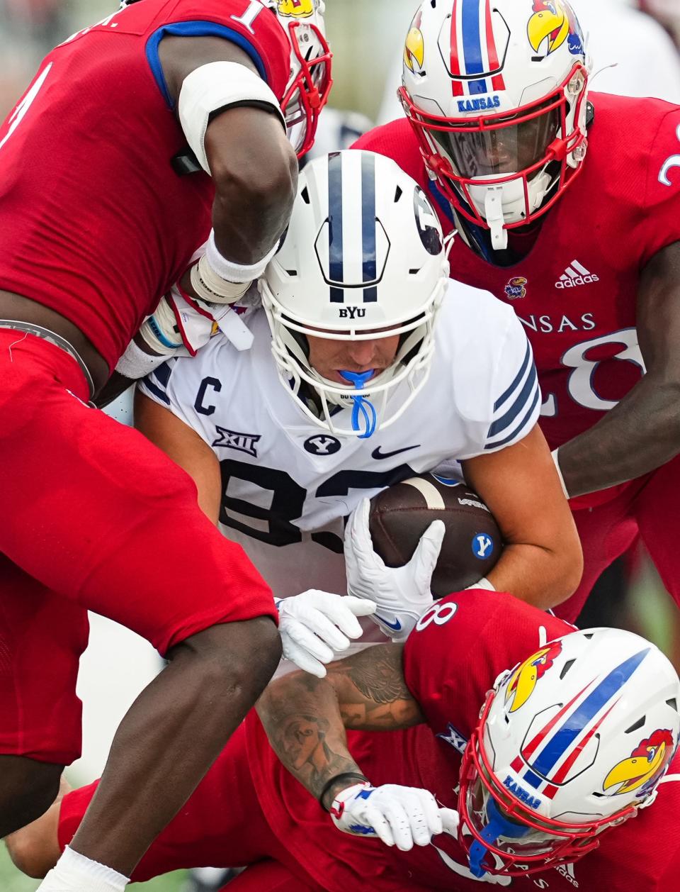 September 23, 2023;  Lawrence, Kansas, USA;  BYU football tight end Isaac Rex (83) is tackled by Kansas safety Kenny Logan Jr. (1), cornerback Kwinton Lassiter (8) and linebacker JB Brown (28) during the first half of a game on September 23, 2023 at David Booth Memorial Stadium Kansas.