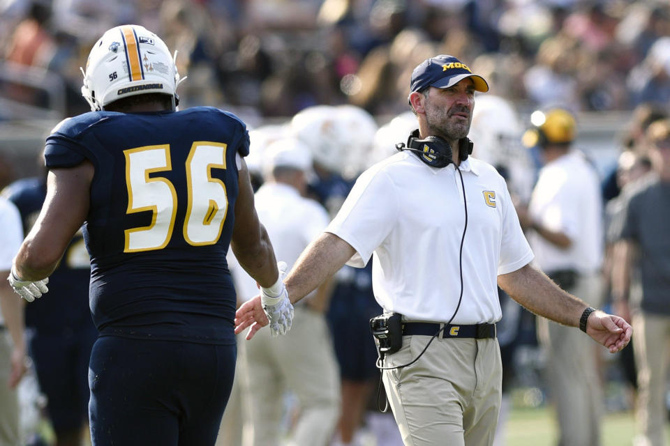 Chattanooga NCAA college football assistant coach Chris Malone congratulates Malcom White (56) after a touchdown during a college football game against Western Carolina in Chattanooga, Tenn., in this Sept. 28, 2019, file photo. The Chattanooga football assistant coach fired over a social media post disparaging the state of Georgia and voting rights advocate Stacey Abrams is suing to get his job back along with back pay and damages. He contends his First Amendment rights were violated. Malone says he was forced to resign Jan. 7 in the lawsuit filed Tuesday, April 27, 2021, in the Eastern District of U.S. District Court. (Robin Rudd/Chattanooga Times Free Press via AP)