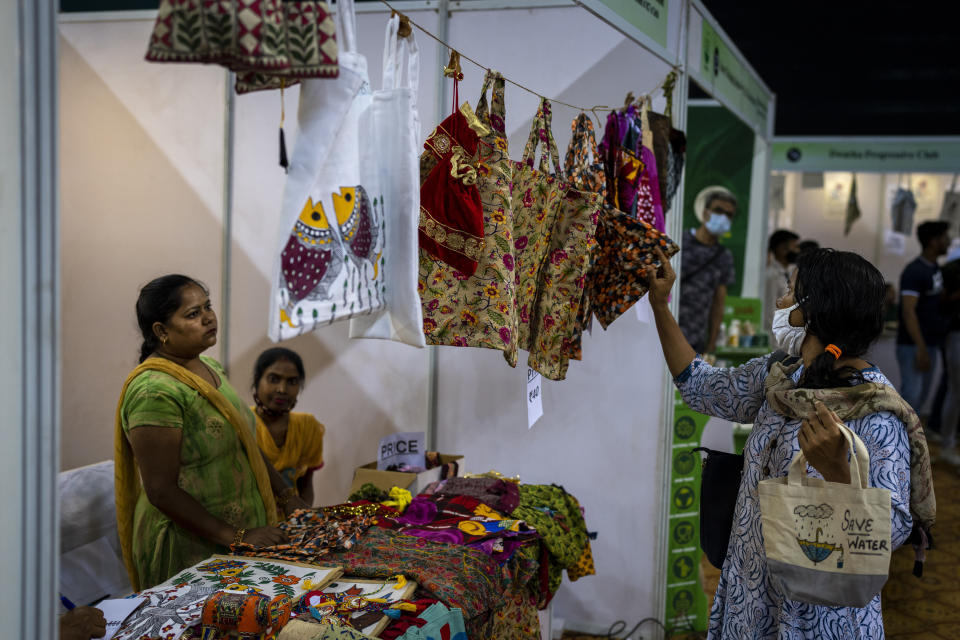 A woman checks out bags made of cloth and jute at an event to create awareness about eco-friendly products in New Delhi, India, Friday, July 1, 2022. India banned some single-use or disposable plastic products Friday as part of a federal plan to phase out the ubiquitous material in the nation of nearly 1.4 billion people. (AP Photo/Altaf Qadri)