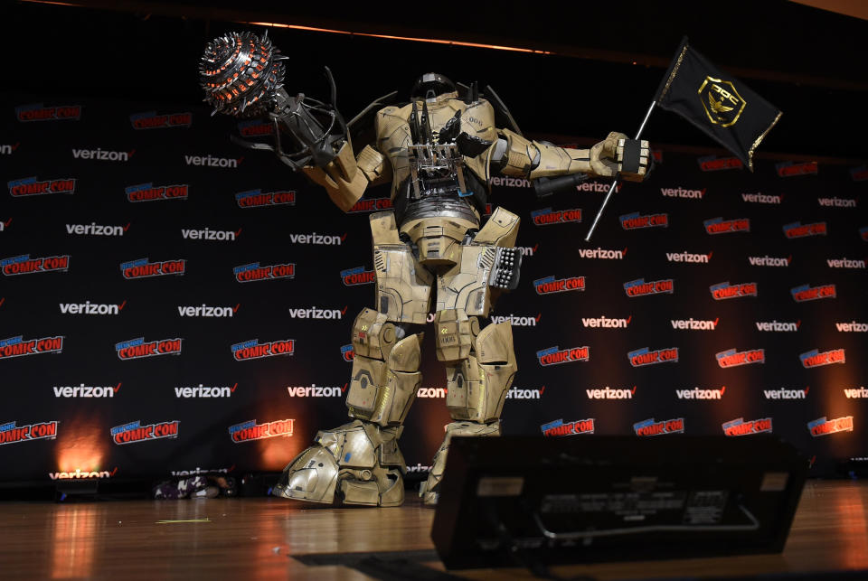 A fan shows off a massive robot outfit on stage.