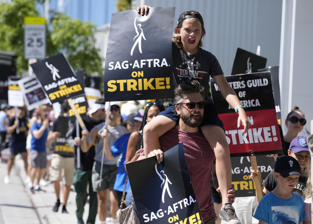 FILE - Director of Photography Jac Cheairs and his son, actor Wyatt Cheairs, 11, take part in a rally by striking writers and actors outside Netflix studio in Los Angeles on Friday, July 14, 2023. (AP Photo/Chris Pizzello, File)