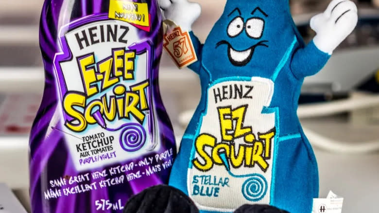 A bottle of Heinz purple ketchup and plushy of Heinz blue ketchup