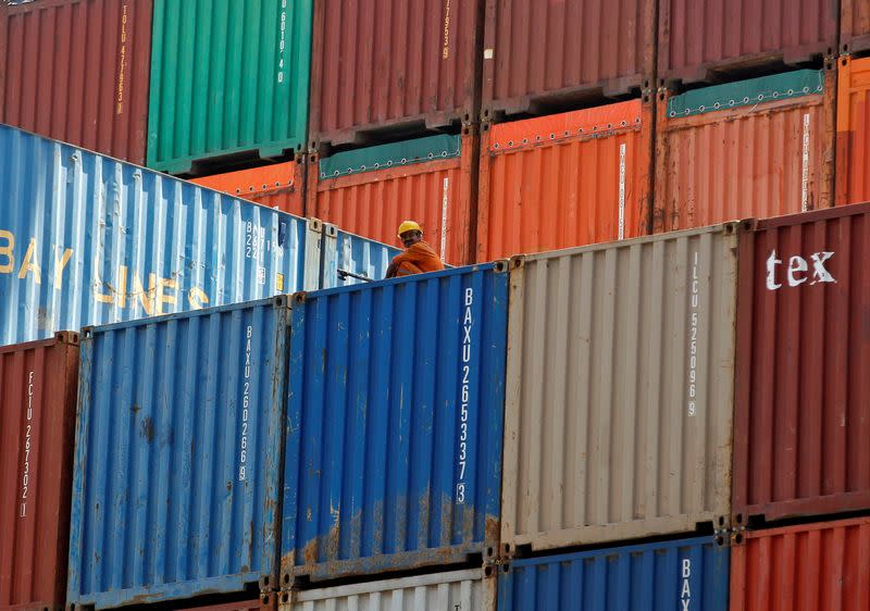 FILE PHOTO: A worker sits on a ship carrying containers at Mundra Port in the western Indian state of Gujarat