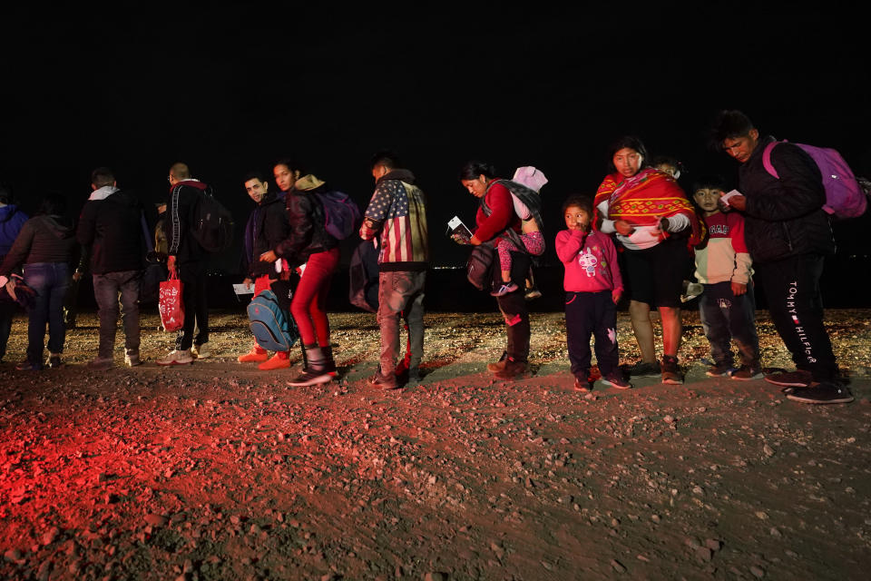 Migrants wait to be processed after crossing the border Friday, Jan. 6, 2023, near Yuma, Arizona. The Biden administration on Thursday launched an online appointment system for migrants to be exempt from limits on seeking asylum, its latest major step in eight days to overhaul border enforcement. (AP Photo/Gregory Bull)