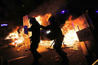 Policemen move as a police van runs over a burning barricade during clashes between protestors and police in Barcelona, Spain, Wednesday, Oct. 16, 2019. Spain's government said Wednesday it would do whatever it takes to stamp out violence in Catalonia, where clashes between regional independence supporters and police have injured more than 200 people in two days. (AP Photo/Bernat Armangue)